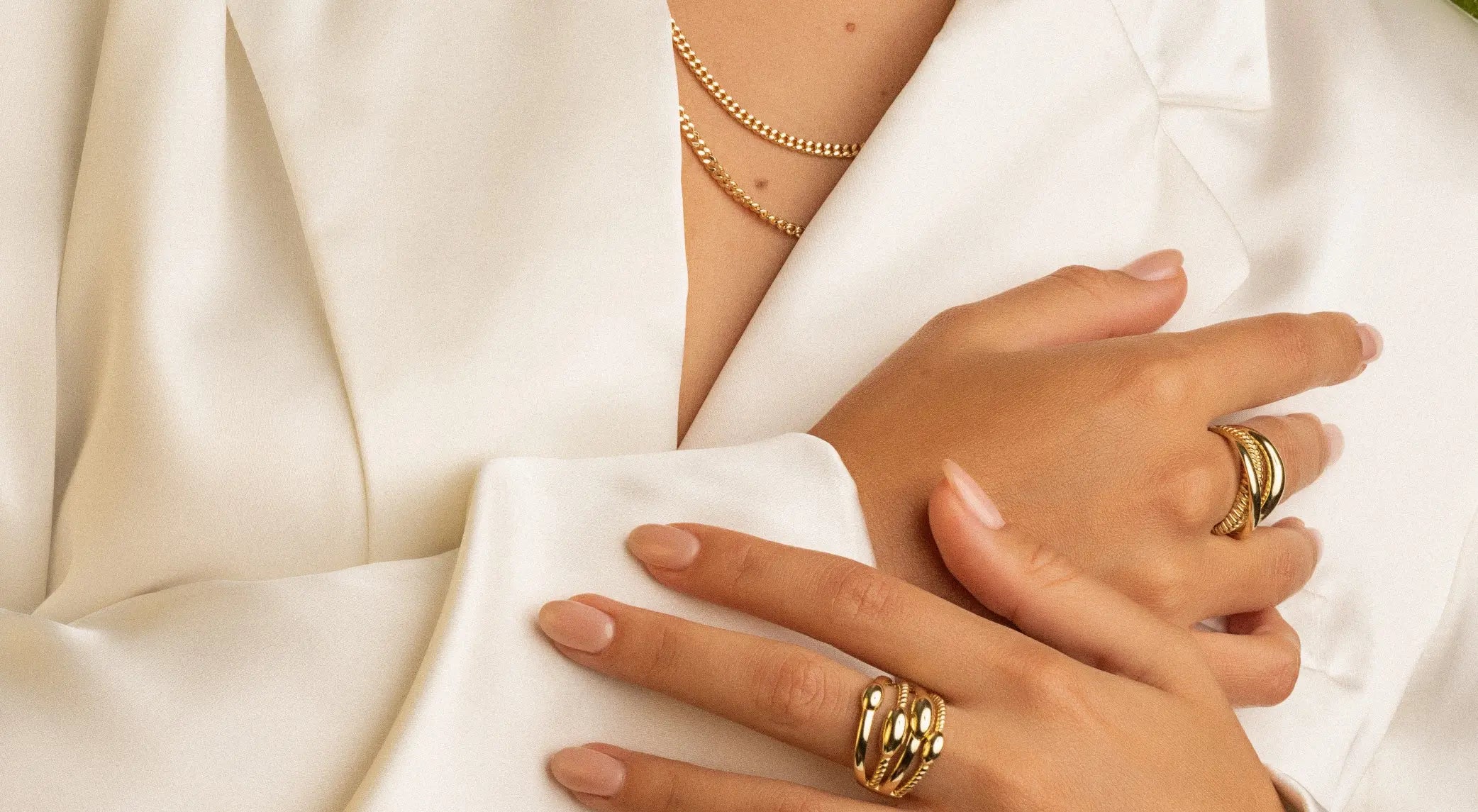Close-up of hands wearing gold rings on a white fabric background